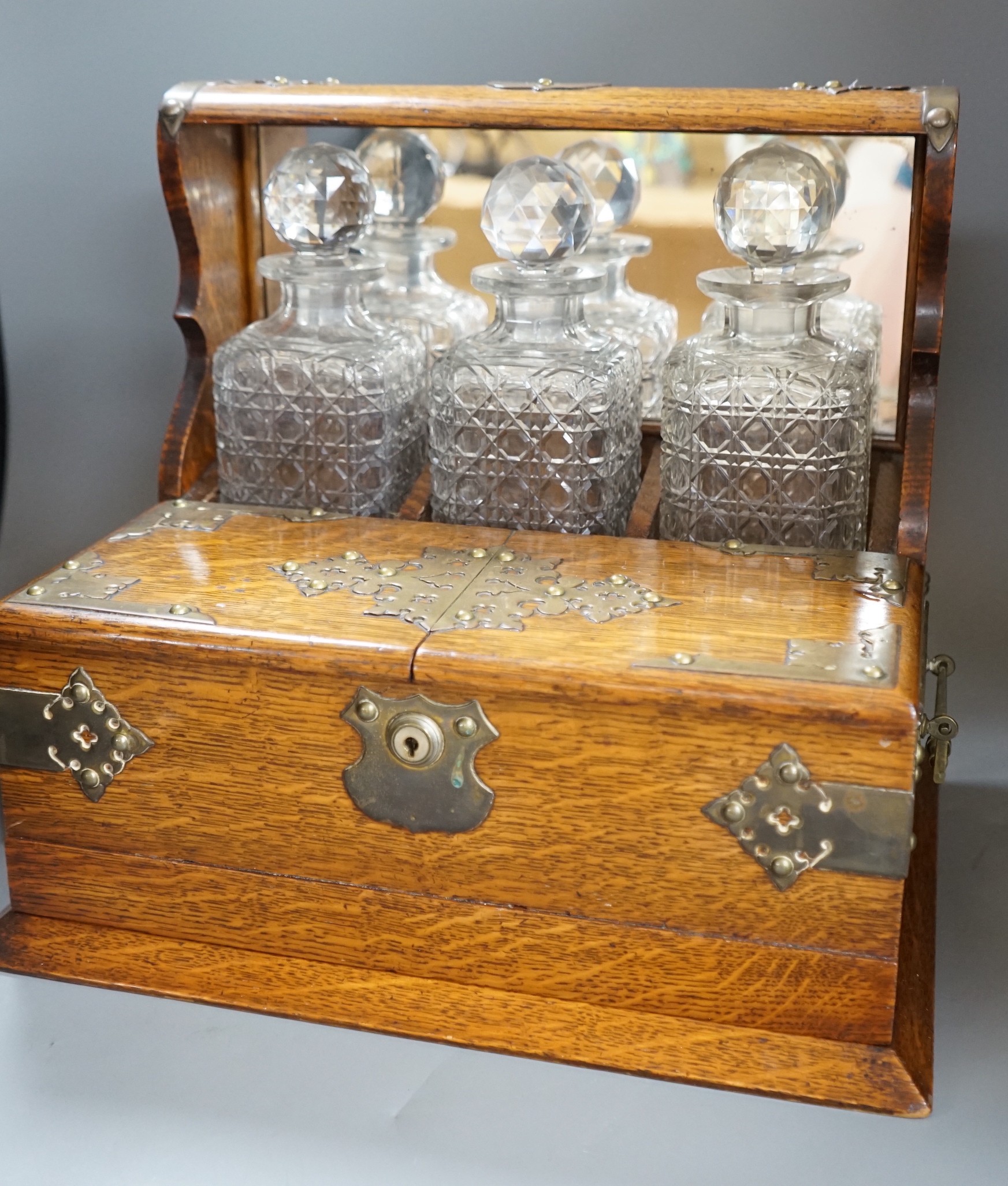 A Victorian brass mounted oak three bottle tantalus, 38cm